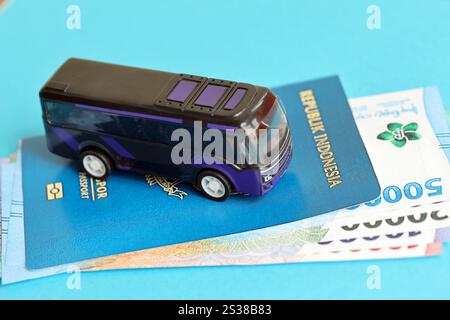 Blauer Indonesien-Pass mit Geld und Spielzeugbus auf blauem Hintergrund Nahaufnahme. Tourismus und Reisekonzept. Pass der Blauen Republik Indonesien Stockfoto