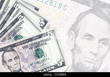 5 US-Dollar-Scheine liegen im Stapel auf dem Hintergrund der großen halbtransparenten Banknote. Abstrakter Geschäftshintergrund mit Kopierbereich Stockfoto