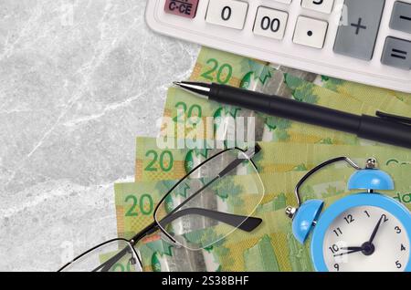 20 kanadische Dollarscheine und Taschenrechner mit Brille und Stift. Geschäftsdarlehen oder Steuerzahlung Saisonkonzept. Finanzplanung und Zeit für die Zahlung von Steuern. Stockfoto