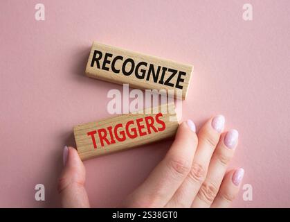 Symbol Auslöser erkennen. Konzeptwörter erkennen Auslöser auf Holzblöcken. Geschäftsmann Hand. Schöner rosafarbener Hintergrund. Business und Anerkennung Trig Stockfoto