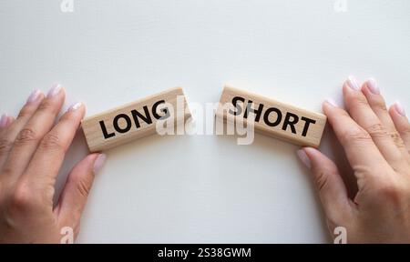 Symbol kurz vs lang. Konzeptwort kurz vs lang auf Holzblöcken. Geschäftsmann Hand. Schöner weißer Hintergrund. Business und kurz- vs Langkonzept. C Stockfoto