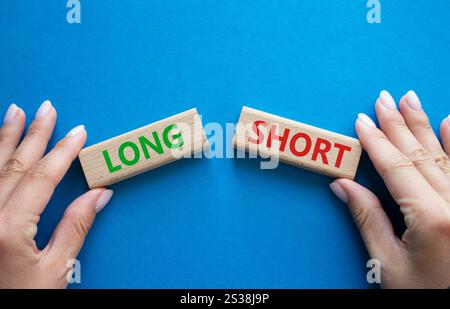 Symbol kurz vs lang. Konzeptwort kurz vs lang auf Holzblöcken. Geschäftsmann Hand. Wunderschöner blauer Hintergrund. Business und kurz- vs Langkonzept. Co Stockfoto