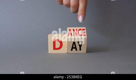 Symbol für den Internationalen Tanztag. Die Hand des Geschäftsmannes zeigt auf gedrehte Holzwürfel mit den Worten Dance Day. Schöner grauer Hintergrund. Internationaler Tanz Da Stockfoto