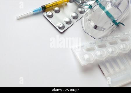 Coronavirus-Behandlungskonzept. Eine medizinische Gesichtsmaske Vernebler für die Behandlung der Atemwege und Packs von Ampullen flach auf einem weiß gelegt Stockfoto