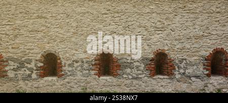 Sehr altes Fenster in Ziegelsteinmauer der Burg oder Festung aus dem 18. Jahrhundert. Vollrahmenwand mit Nahaufnahme des Fensters. Sehr altes Fenster in einer Ziegelsteinmauer Stockfoto