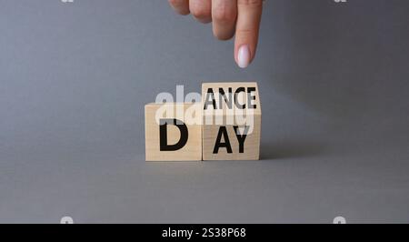 Symbol für den Internationalen Tanztag. Die Hand des Geschäftsmannes zeigt auf gedrehte Holzwürfel mit den Worten Dance Day. Schöner grauer Hintergrund. Internationaler Tanz Da Stockfoto