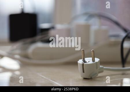 Überlastete Stromversorgungsplatinen. Steckdosenleisten mit verschiedenen Steckern auf weißem Boden. Konzept der Gefahr Gefahr Überlaststrom elektrisch. Stockfoto