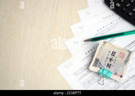 Japanische Steuerformulare liegen auf dem Tisch mit Taschenrechner, Stift und japanischen Yen-Geldscheine werden aus nächster Nähe herangezogen. Japanische Steuerformulare liegen auf dem Tisch mit Rechner, Stockfoto