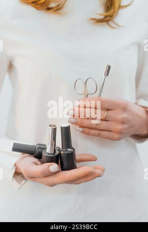 Nahaufnahme der Hände einer Frau mit Manikürenwerkzeugen und Gel-polierflaschen. Perfekt gepflegte Nägel zeigen Eleganz und Liebe zum Detail, ideal Stockfoto