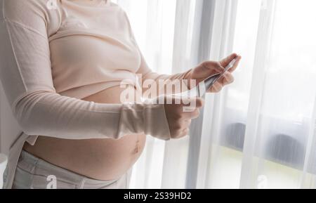 Schwangere asiatische Frau, die Ultraschall-Baby hält Bild Ergebnis vom Arzt. Happy Mom Health Care Konzept. Stockfoto
