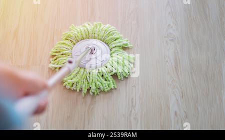 Hochwinkelansicht einer jungen Frau, die im Schlafzimmer mit Mopp den Boden wäscht, selektiver Fokus auf das Thema. Reinigungsservice-Konzept. Stockfoto