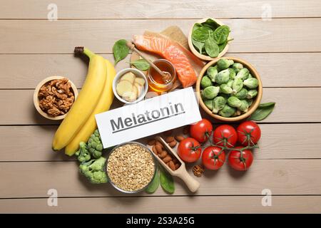 Wort Melatonin und verschiedene Produkte auf Holztisch, flach gelegt Stockfoto