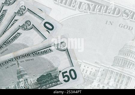 50 US-Dollar-Scheine liegen auf dem Hintergrund einer großen halbtransparenten Banknote im Stapel. Abstrakter Geschäftshintergrund mit Kopierbereich Stockfoto