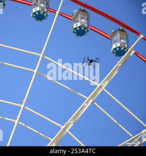 Drohne mit Fotokamera startet vom Land und fliegt für Fotos vor dem Riesenrad. Die Drohne startet vom Land und fliegt, um Fotos zu machen Stockfoto