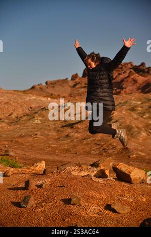 Eine touristische Frau posiert in dem rot gefärbten felsigen Vulkangebiet, ähnlich der rosa Mars-Landschaft auf der Insel Madeira, Portugal. Stockfoto