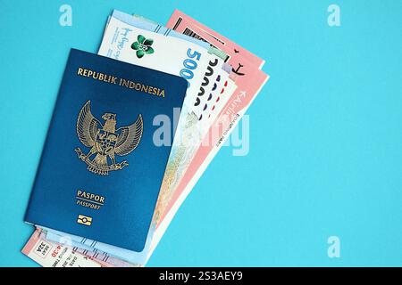 Blauer Indonesien Pass mit Geld und Flugtickets auf blauem Hintergrund Nahaufnahme. Tourismus und Reisekonzept. Blaue Republik Indonesien Stockfoto