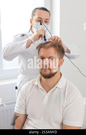 Alopezie. Der Haarausfall des Mannes verbessert die Regeneration der Wachstumsbehandlung, Dermapen-Mikroneedling, Vitamin-Exosomen-Plasmainjektionen. Trichologe Kosmetologe Arzt KopfKopfKopfhautverfahren fraktionelle Mesotherapie Stockfoto