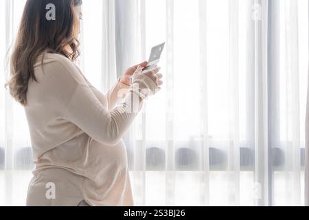Schwangere asiatische Frau, die Ultraschall-Baby hält Bild Ergebnis vom Arzt. Happy Mom Health Care Konzept. Stockfoto