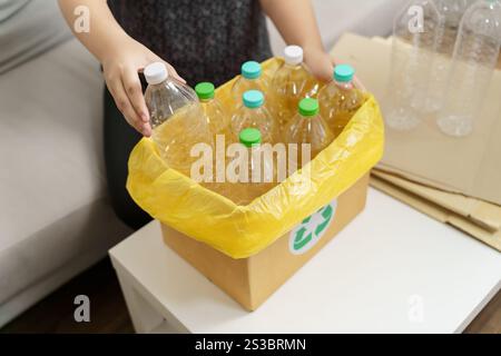 Recyceln Sie die umweltfreundliche Zero Concept Frau, die leere Plastikflasche mit gelben Mülltüten zu Hause in den Recyclingbehälter wirft Stockfoto