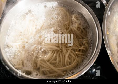 Kochen von Udon-Nudeln in Stahltopf in der Küche zu Hause Stockfoto