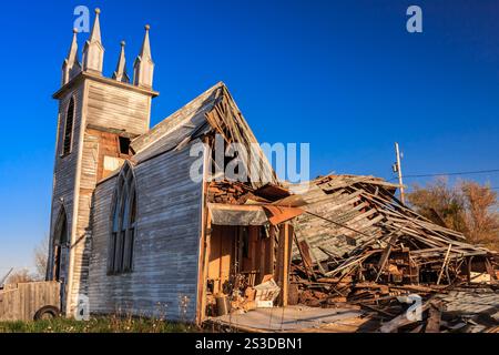 Eine Kirche mit einem Turm und einem kaputten Dach. Auf dem Dach fehlen viele Schindeln und das Gebäude befindet sich in einem Zustand der Verwerfung Stockfoto