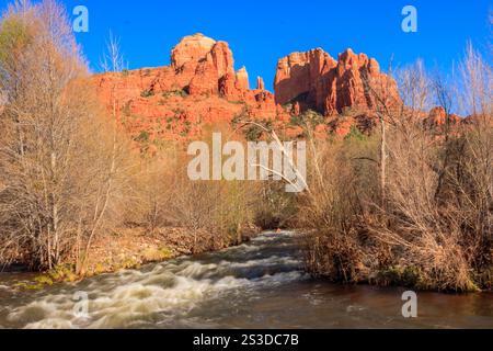 Ein Fluss fließt durch einen Canyon mit einer roten Felsformation im Hintergrund. Das Wasser rauscht und die Felsen sind zerklüftet. Die Szene ist ruhig und erbsenfrei Stockfoto