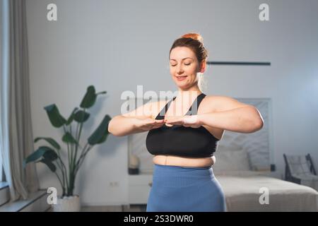 Fitness-Workout-Training. Frau, die zu Hause Fitness übt. Frauen in Übergröße, die zu Hause in der Halle sportlich trainieren. Mädchen in Sportbekleidung haben Workout Gewichtstraining zur Gewichtsreduktion. Sport und Fitness Stockfoto