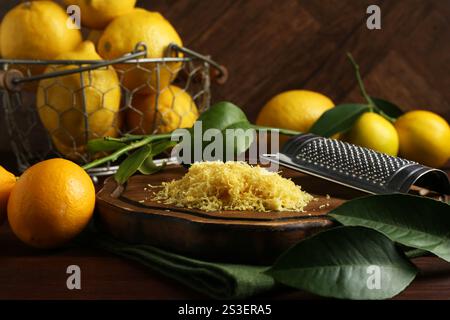 Zitronenschale, Reibe und frisches Obst auf Holztisch Stockfoto