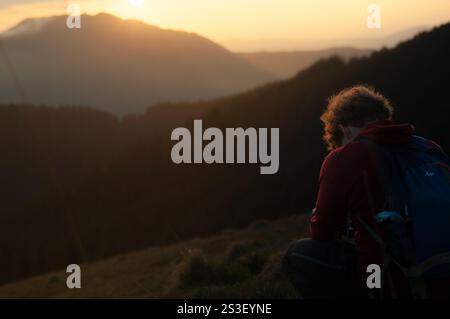 Silhouette eines Fotografen bei Sonnenaufgang in den Bergen, der goldenes Licht und nebelige Schönheit in einer ruhigen und inspirierenden Outdoor-Szene einfängt. Stockfoto