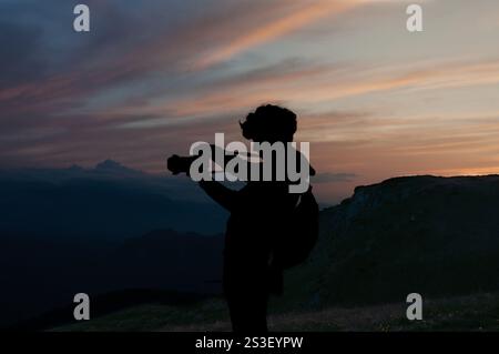 Silhouette eines Fotografen bei Sonnenaufgang in den Bergen, der goldenes Licht und nebelige Schönheit in einer ruhigen und inspirierenden Outdoor-Szene einfängt Stockfoto