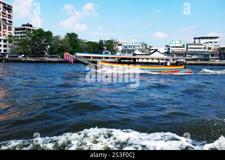 Traditionelles farbenfrohes thailändisches Langschwanz-Passagierboot, das an einem sonnigen Nachmittag auf dem Chao-Phraya-Fluss in Bangkok, Thailand, kreuzt. Stockfoto