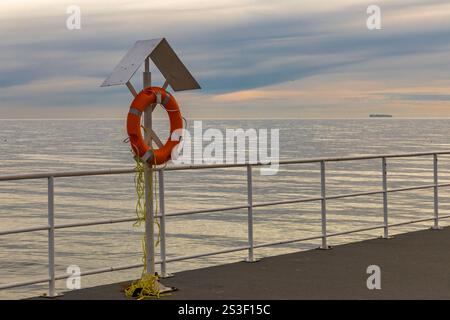 Spazieren Sie entlang der Küste von Gdynia nach Gdynia Orlowo, Rettungsring hängt am Wellenbrecher, orangefarbener Rettungsring vom Schiff zum Pier Stockfoto