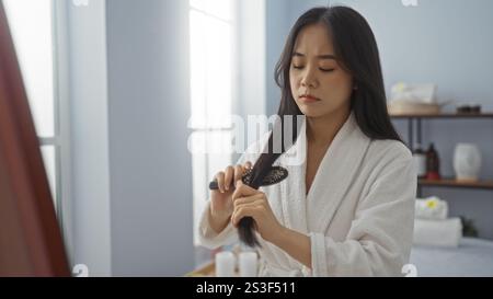 Frau putzt Haare im Spa-Zimmer mit weißem Bademantel Stockfoto