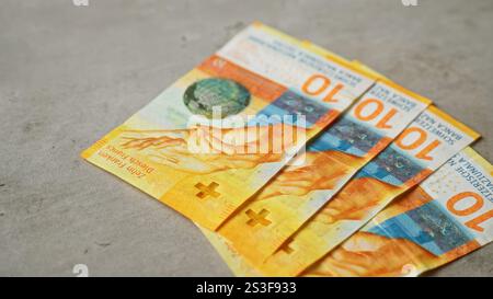 Vier schweizer-Franken-Banknoten liegen auf einer Betonoberfläche mit leuchtenden Farben und komplexen Designdetails, die auf die schweizer Währung hinweisen. Stockfoto