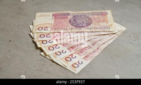 Polnische Banknoten im Wert von 20 Zloty verteilen sich auf einer Betonoberfläche, wobei die Währung, das Finanzwesen und die polnische Wirtschaft hervorgehoben werden. Stockfoto