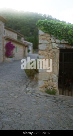 auf mallorca, spanien, verwischt die Szene im Freien, mit Steinbauten und üppigem Laub auf einer gepflasterten Straße bei Sonnenaufgang oder Abenddämmerung. Stockfoto