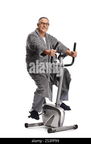 Reifer Mann in einem Bademantel, der auf weißem Hintergrund auf einem Fitnessrad fährt Stockfoto