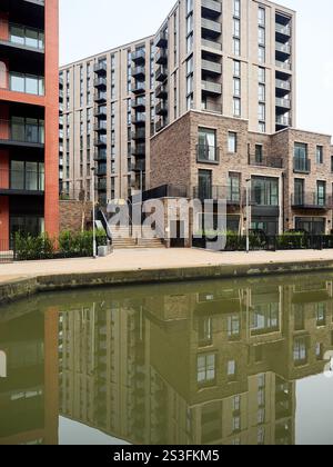 Salford , Manchester, Großbritannien, 01-04-2025: Middlewood Locks. Moderne Apartmenthäuser spiegeln sich in einer ruhigen urbanen Kanalszene wider. Stockfoto