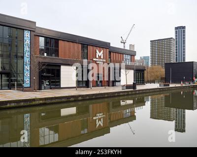 Salford , Manchester, Großbritannien, 01-04-2025: Middlewood Locks. Moderne Gebäude am Wasser spiegeln sich in einem ruhigen Kanal unter bewölktem Himmel wider. Stockfoto