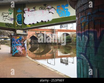 Salford , Manchester, Großbritannien, 01-04-2025: Mit Graffiti bedeckte Flussunterführung, die eine Mischung aus urbaner Kunst und Architektur widerspiegelt. Stockfoto