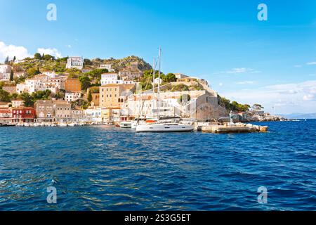 Boote am Pier mit farbenfrohen und historischen Steinbauten entlang der Strandpromenade in der Nähe von alten Mauern und Bastionen auf der Insel Hydra Greece Stockfoto