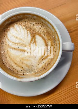 Dieses Foto zeigt eine wunderschön gefertigte Tasse Latte, verziert mit komplizierten Latte Art, die an einem sonnigen Frühlingstag in Istanbul serviert wird. Der schaumige des Stockfoto