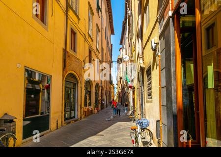 Eine enge Fußgängerzone mit Geschäften und Boutiquen in der historischen mittelalterlichen Altstadt von Lucca, Italien, in der Toskana. Stockfoto