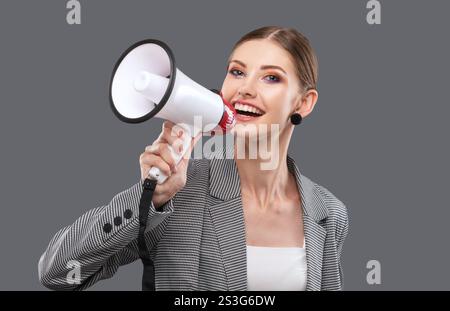 Ein schönes, fröhliches Mädchen ruft in den Lautsprecher auf isoliertem rosa Hintergrund. Stockfoto