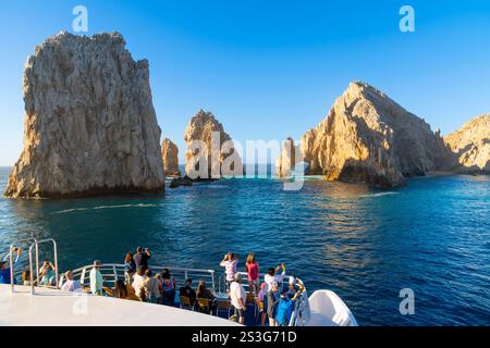 Touristen auf einem Ausflugsboot genießen den Blick auf die Halbinsel Land End und den Arco Arch in Baja California's Ferienort Cabo San Lucas, Mexiko. Stockfoto