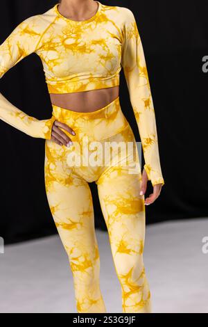 Trendiges gelbes Activewear-Set mit Krawattenmuster, Langarm-Oberteil und Leggings, modischem Trainingsoutfit, Activewear-Konzept Stockfoto