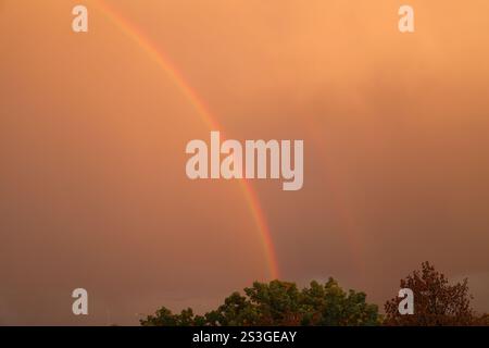rainbow erscheint in einem rötlich-braunen, rauchigen Himmel Stockfoto