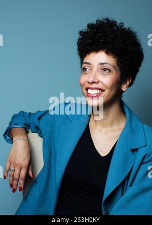 Erfolgreiche Geschäftsfrau, die entspannt auf einem Stuhl sitzt. afroamerikanisches weibliches Model mit kurzen lockigen Haaren trägt Bürokleidung. Stockfoto