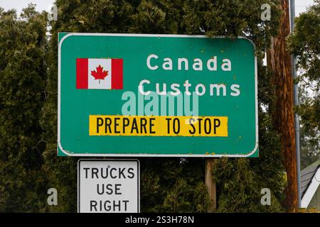Sumas, WA, USA - 8. Januar 2025; USA Kanada Zollgrenzübergang bereiten sich vor, Straßenschild mit kanadischer Flagge zu stoppen Stockfoto