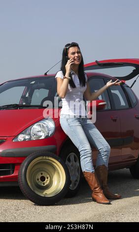 Eine junge Frau mit einem Platten Reifen auf ihrem Auto Stockfoto